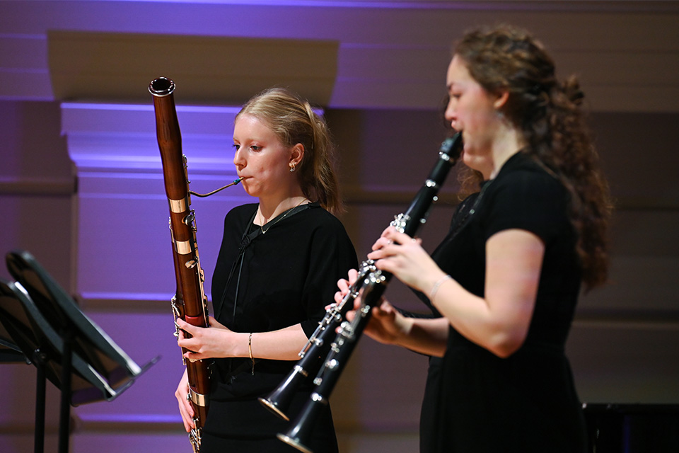 A bassoonist and two clarinets wear black and perform their instruments