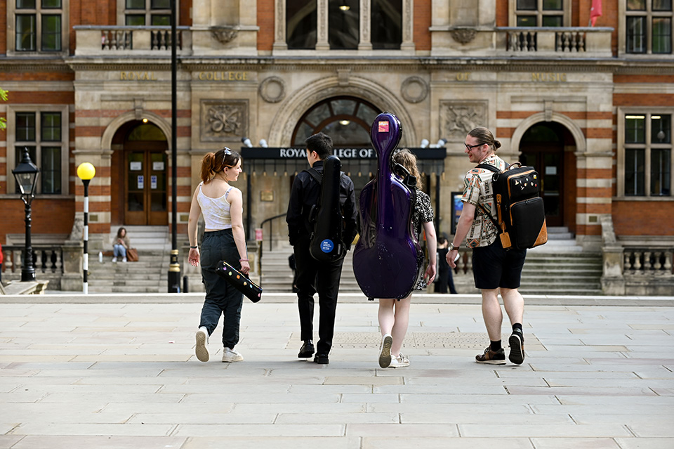 Four students smiling and laughing as they walk towards a prestigious looking building 