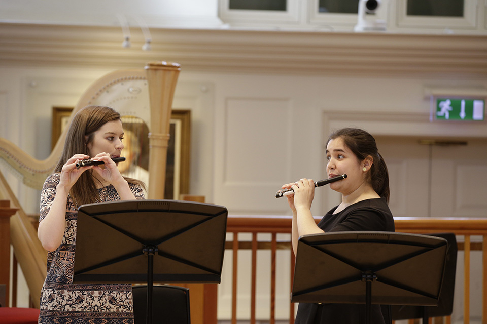 Two students playing the piccolo towards each other